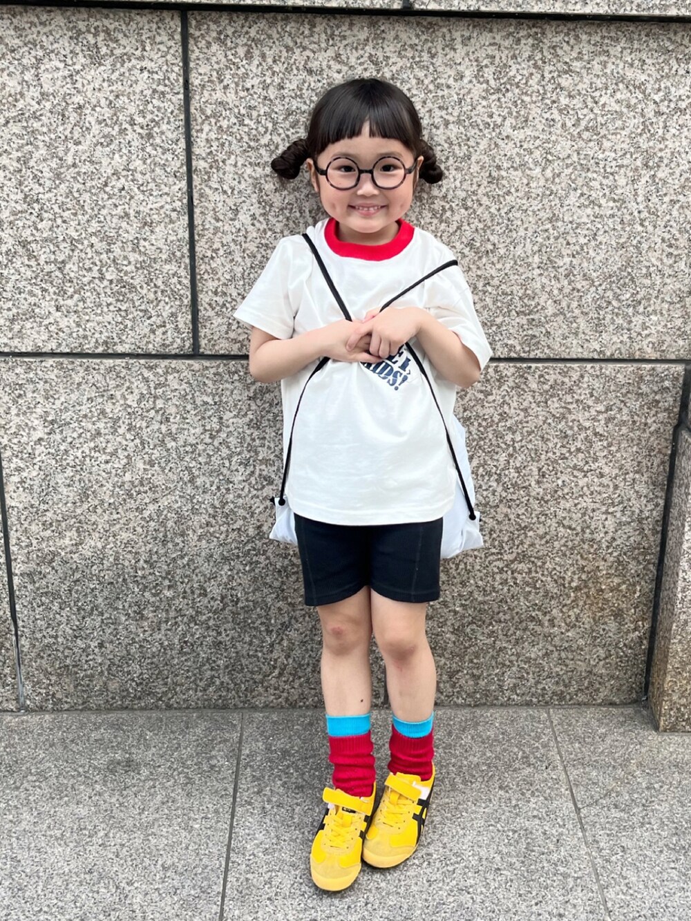 ホワイト系のTシャツ/カットソー、ホワイト系のバックパック/リュック、イエロー系のスニーカーを着用したキッズの春コーディネートの2枚目の写真