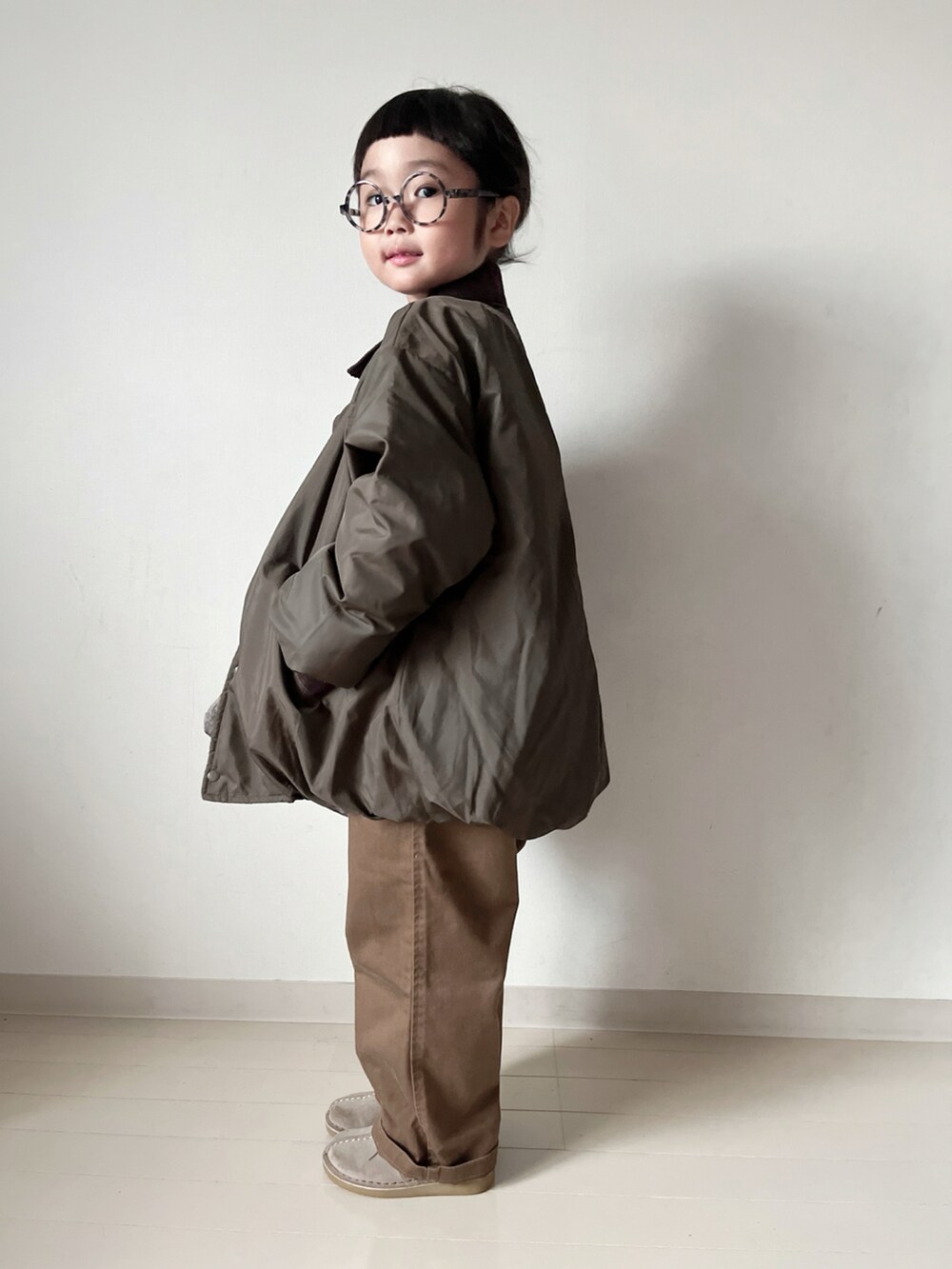 グリーン系のブルゾン、ホワイト系のTシャツ/カットソー、ブラウン系のショルダーバッグを着用したキッズの秋コーディネートの2枚目の写真