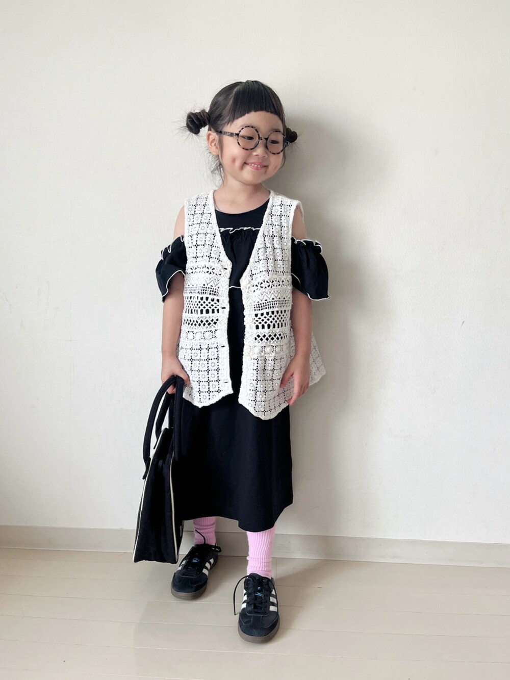 ブラック系のワンピース、ホワイト系のベスト、ホワイト系のハンドバッグを着用したキッズの春コーディネートの3枚目の写真