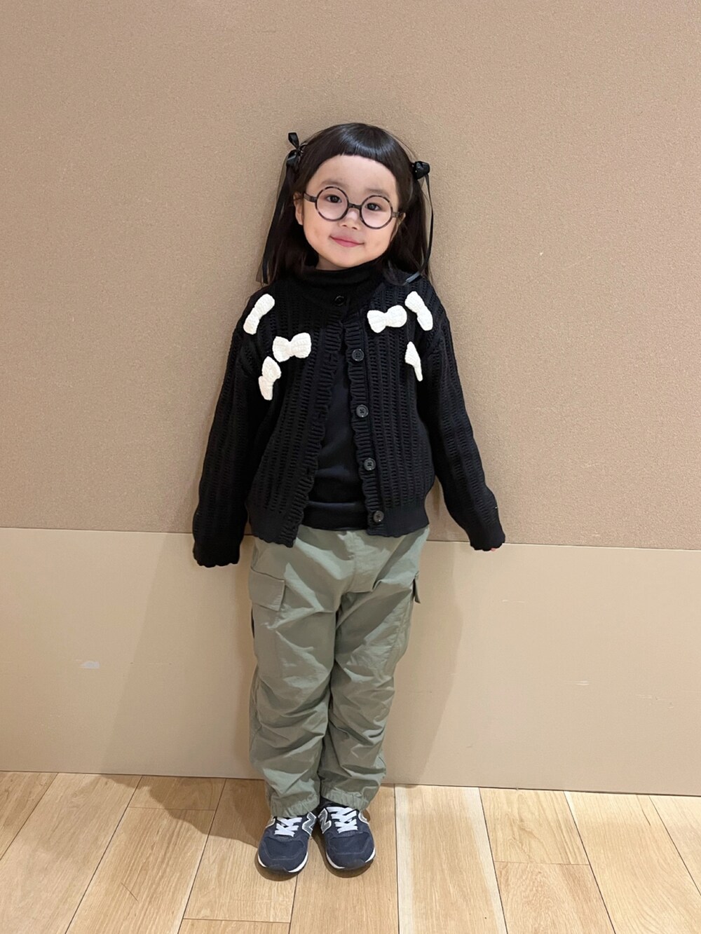 ブラック系のTシャツ/カットソー、ブラック系のカーディガン/ボレロ、グリーン系のカーゴパンツを着用したキッズの冬コーディネートの2枚目の写真