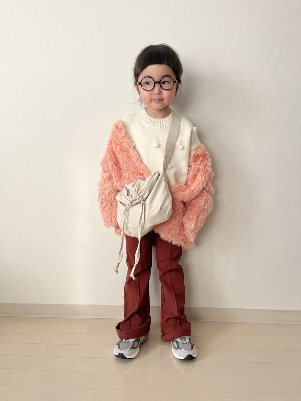 ホワイト系のニット/セーター、オレンジ系のカーディガン/ボレロ、グレー系のスニーカーを着用したキッズの秋コーディネートの2枚目の写真