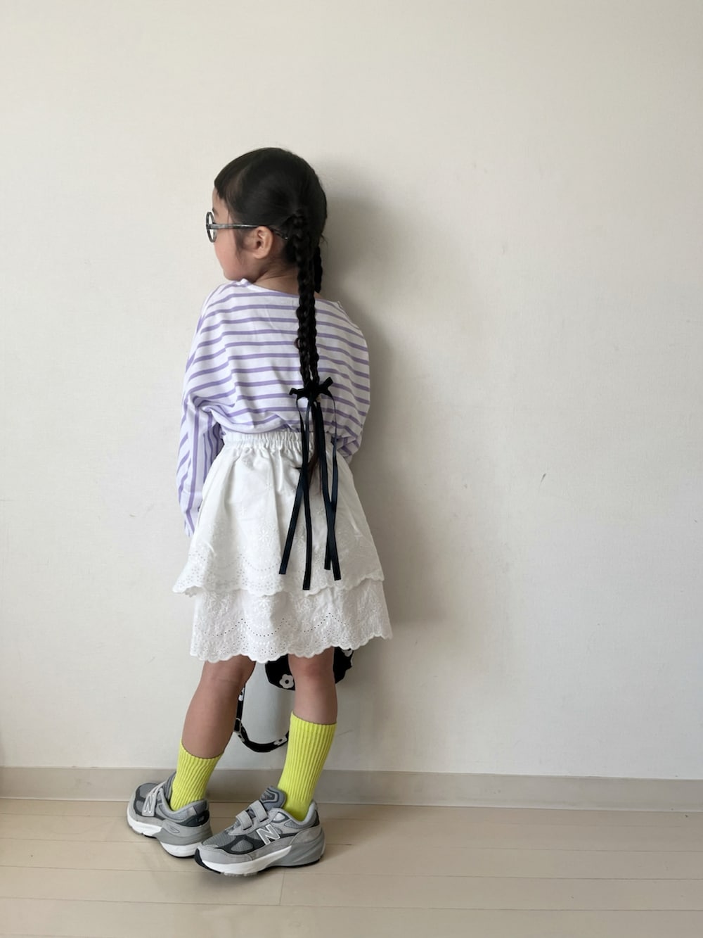 パープル系のTシャツ/カットソー、ホワイト系のスカート、ブラック系のショルダーバッグを着用したキッズの春コーディネートの4枚目の写真