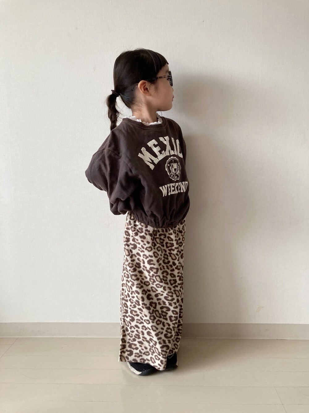 ベージュ系のカーディガン/ボレロ、ベージュ系のTシャツ/カットソー、ブラック系のスニーカーを着用したキッズの冬コーディネートの4枚目の写真