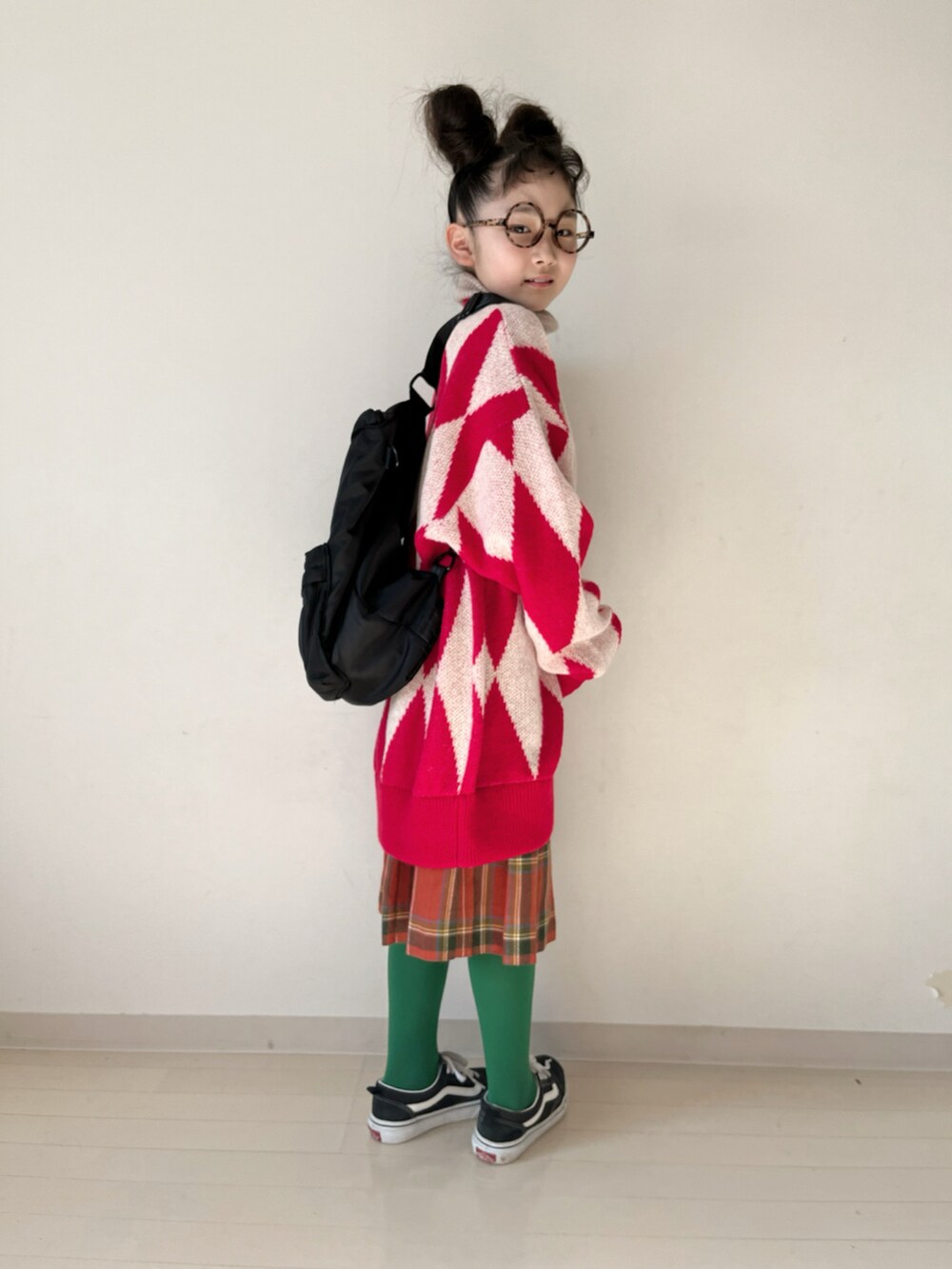 レッド系のカーディガン/ボレロ、レッド系のスカート、ブラック系のスニーカーを着用したキッズの冬コーディネートの2枚目の写真