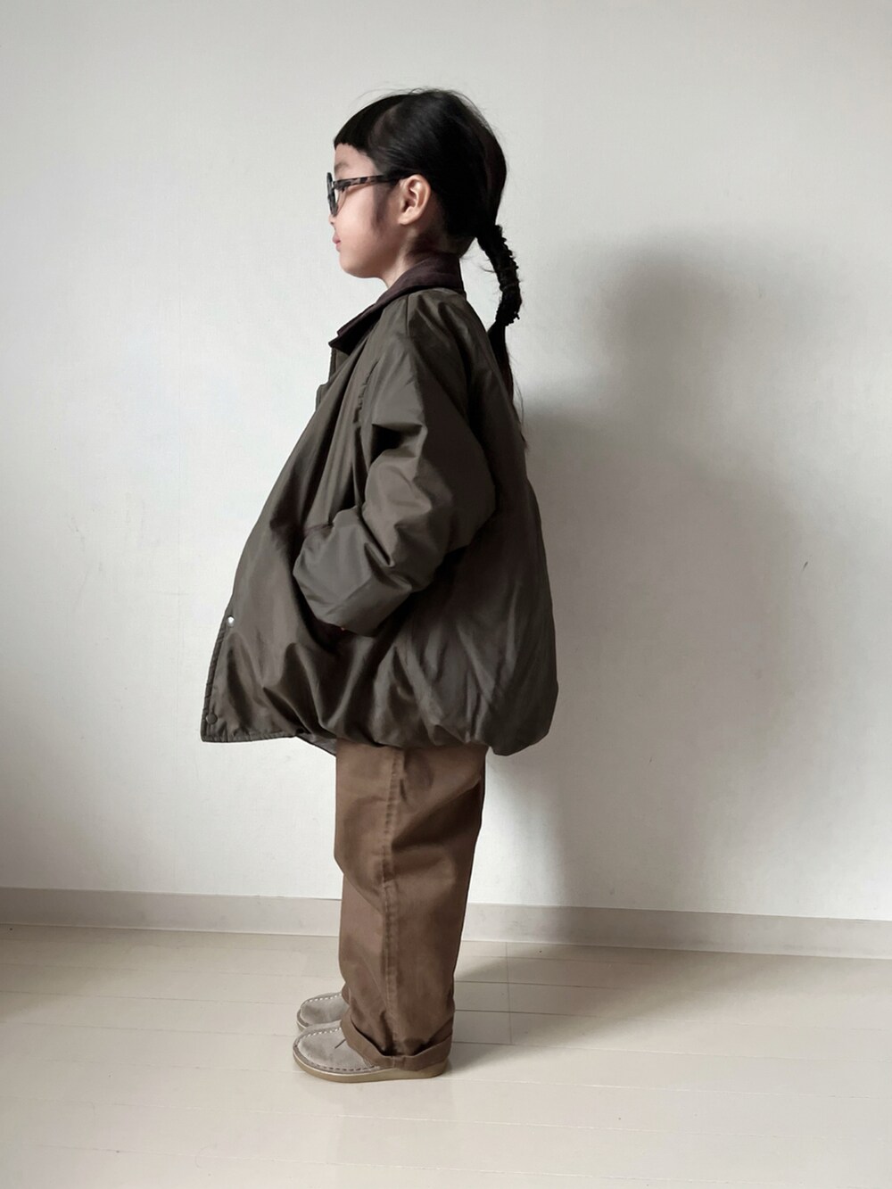 グリーン系のブルゾン、ホワイト系のTシャツ/カットソー、ブラウン系のショルダーバッグを着用したキッズの秋コーディネートの4枚目の写真