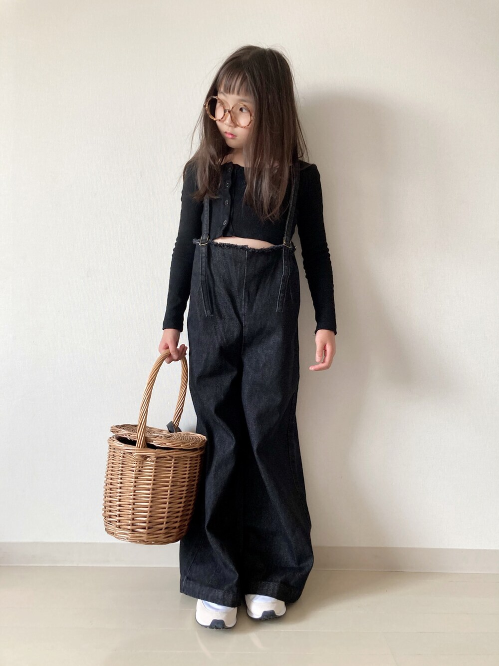 ブラック系のデニムパンツ、ホワイト系のスニーカー、ベージュ系のかごバッグを着用したキッズの夏コーディネートの2枚目の写真