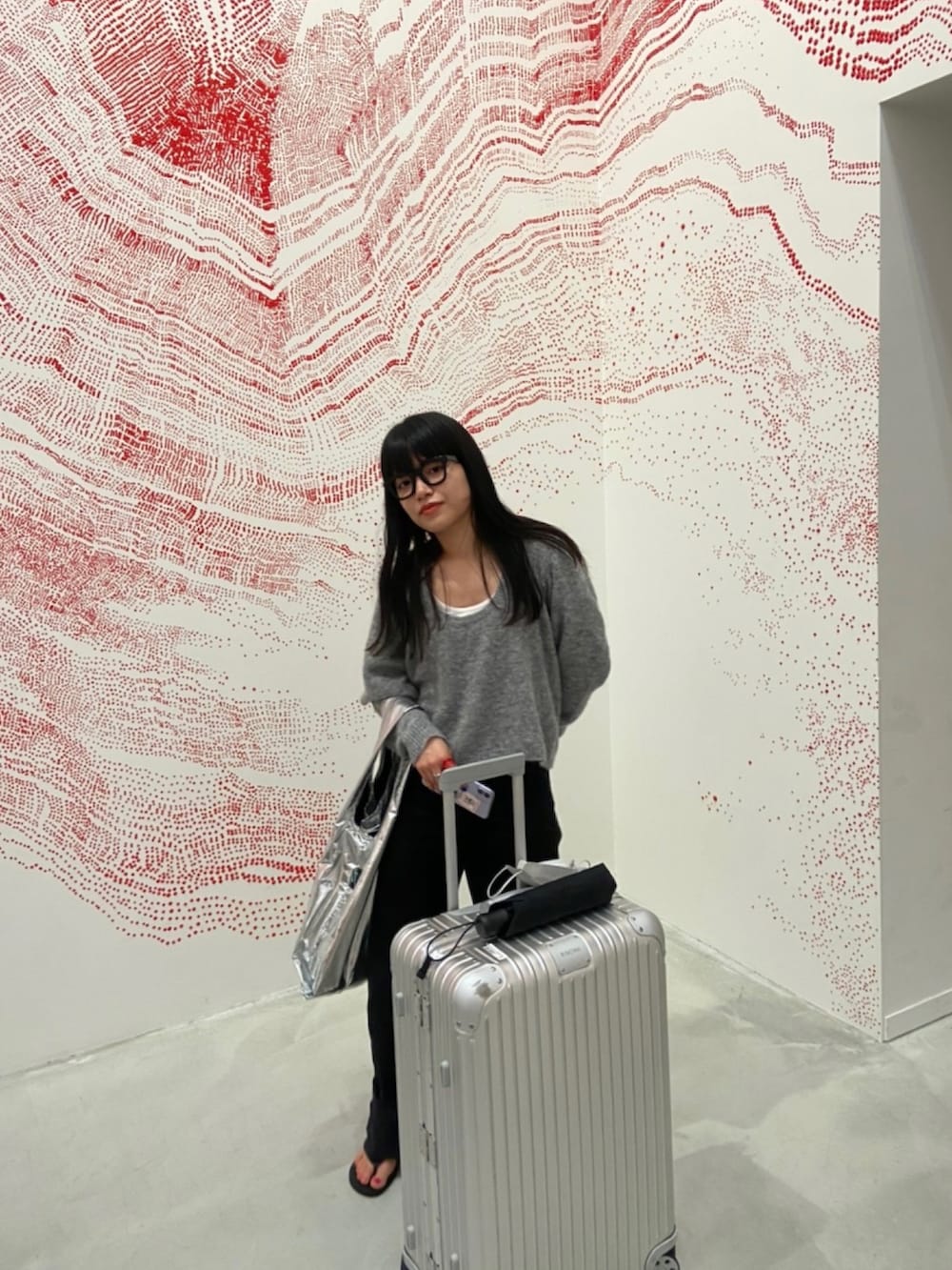 グレー系のニット/セーター、ブラック系のデニムパンツ、シルバー系のエコバッグ/サブバッグを着用したレディースの春コーディネートの2枚目の写真