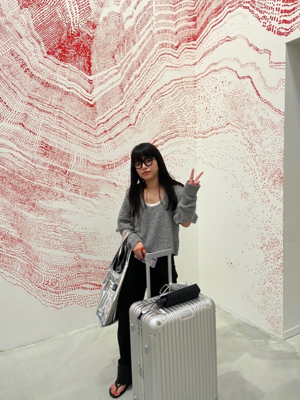 グレー系のニット/セーター、ブラック系のデニムパンツ、シルバー系のエコバッグ/サブバッグを着用したレディースの春コーディネートの3枚目の写真