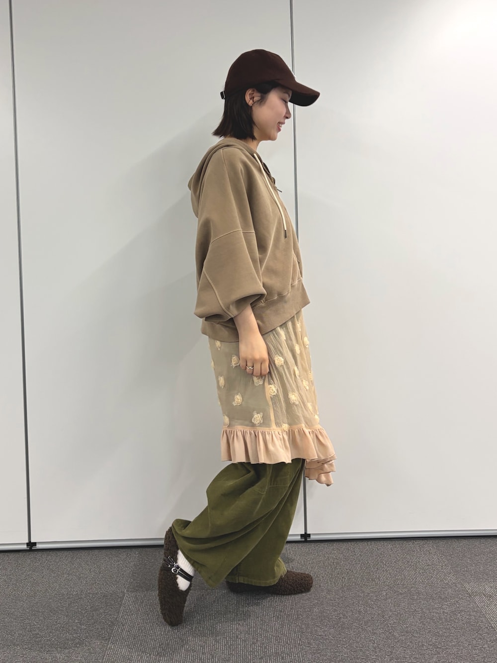 ベージュ系のパーカー、ベージュ系のスカート、グリーン系のその他パンツを着用したレディースの秋コーディネートの2枚目の写真