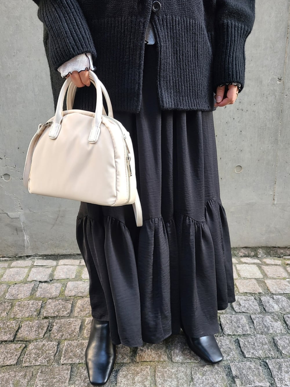 ブラック系のカーディガン/ボレロ、ホワイト系のTシャツ/カットソー、ホワイト系のボストンバッグを着用したレディースの秋コーディネートの4枚目の写真