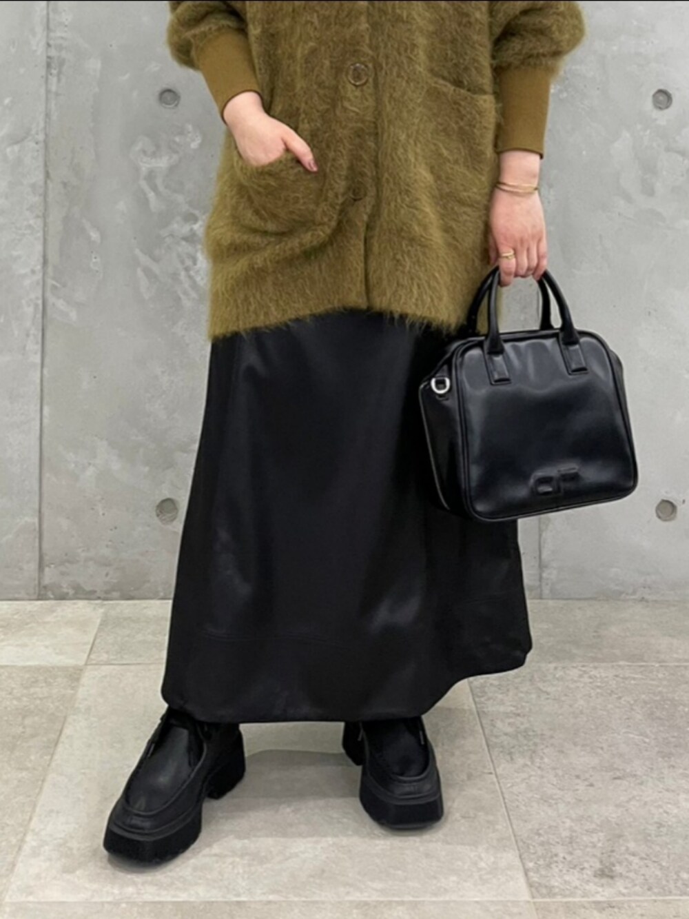 ブラック系のボストンバッグ、ブラウン系のカーディガン/ボレロ、ブラック系のスカートを着用したレディースの秋コーディネートの3枚目の写真