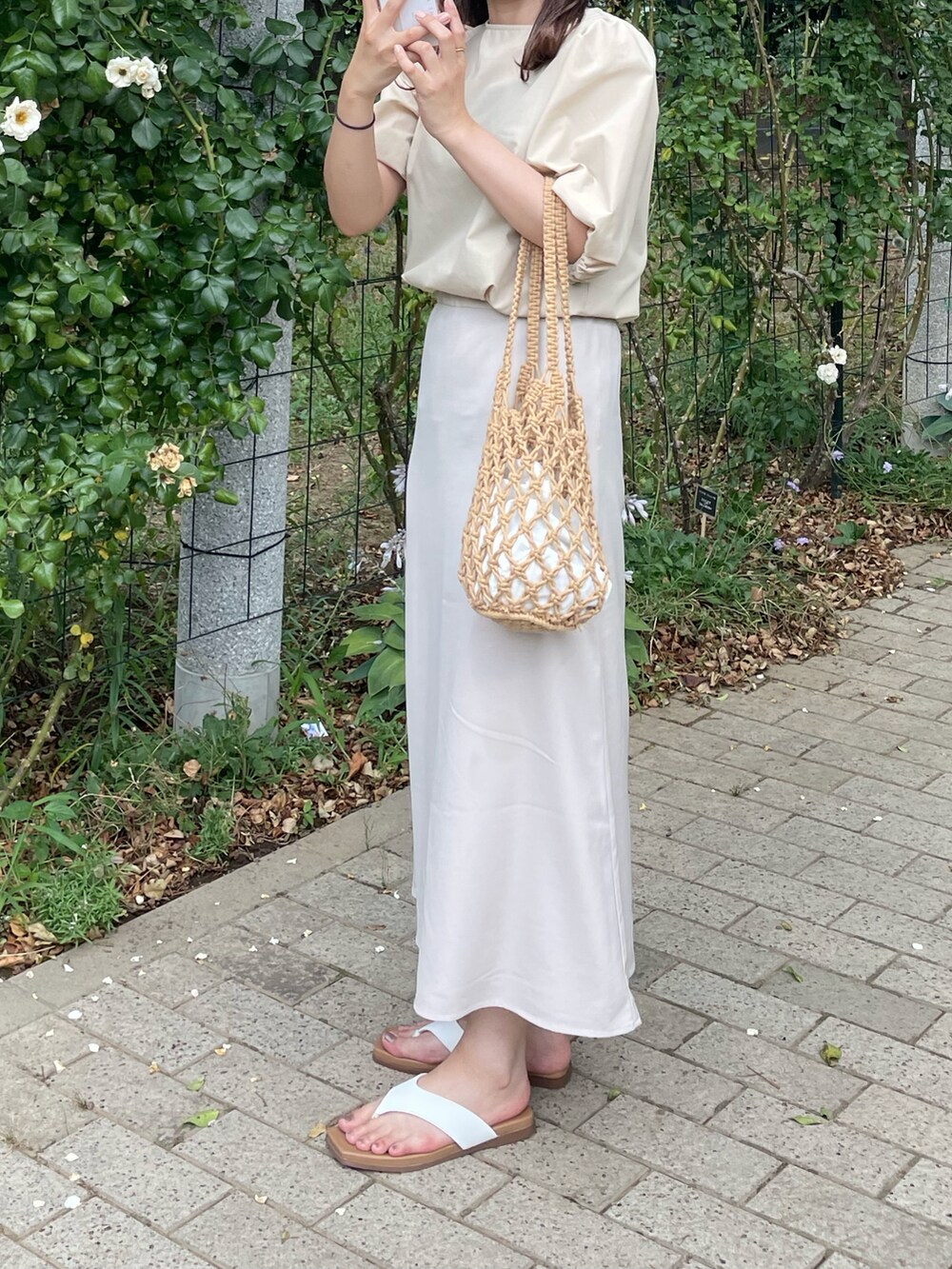 ホワイト系のスカート、ベージュ系のハンドバッグを着用したレディースの夏コーディネートの2枚目の写真
