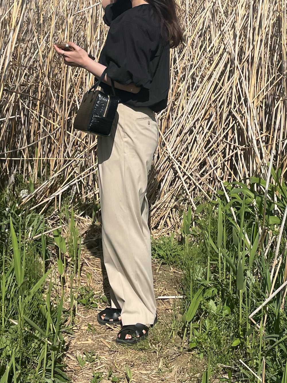 ブラック系のシャツ/ブラウス、ベージュ系のスラックス、ブラック系のサンダルを着用したレディースの春コーディネートの2枚目の写真