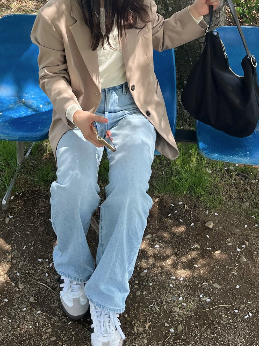 ベージュ系のジャケット/アウター、ブルー系のデニムパンツ、ホワイト系のスニーカーを着用したレディースの春コーディネートの2枚目の写真