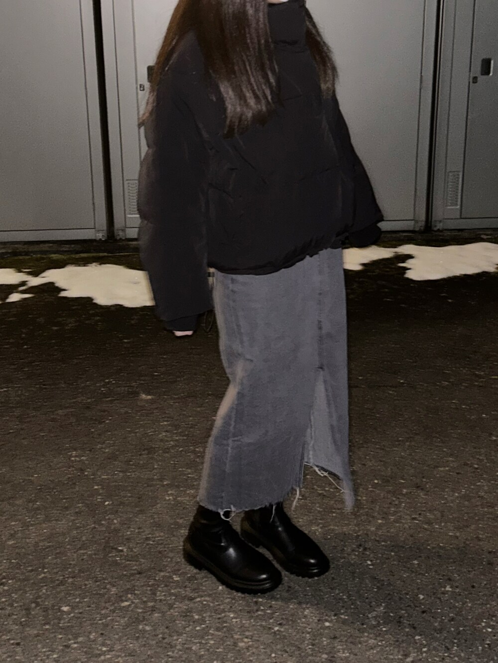 ブラック系のダウンジャケット/コート、グレー系のデニムスカート、ブラック系のブーツを着用したレディースの冬コーディネートの2枚目の写真