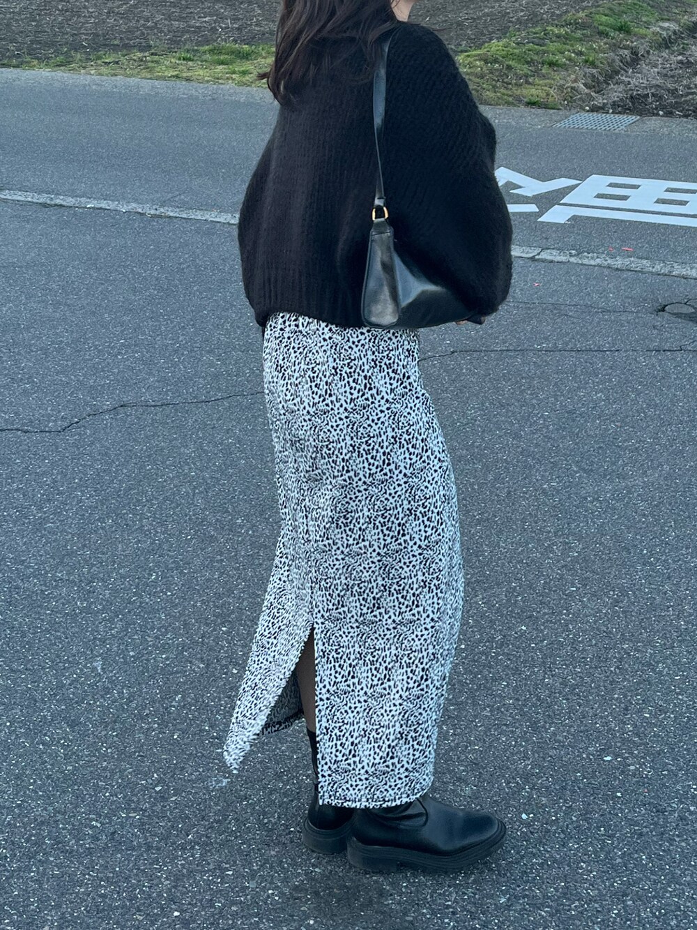 ホワイト系のスカート、ブラック系のニット/セーター、ブラック系のショルダーバッグを着用したレディースの春コーディネートの2枚目の写真