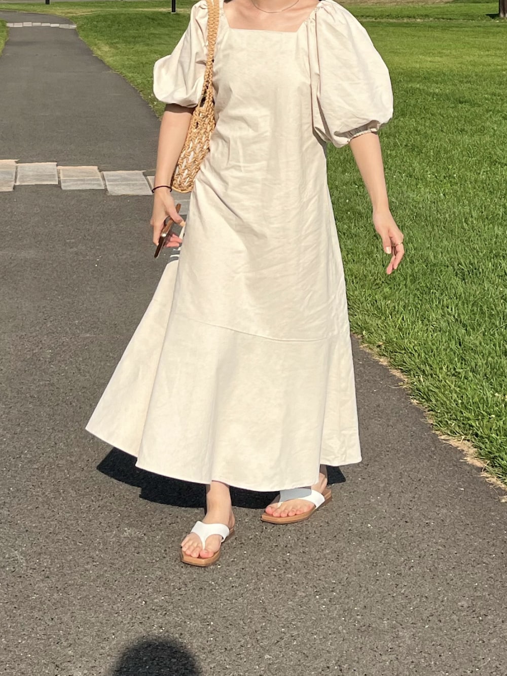 ベージュ系のハンドバッグ、ベージュ系のワンピース、ベージュ系のハットを着用したレディースの夏コーディネートの2枚目の写真