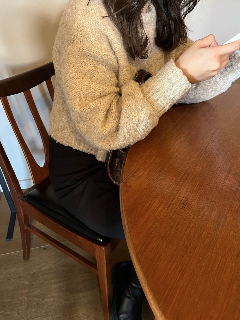 ブラウン系のハンドバッグ、ブラック系のスカート、ベージュ系のニット/セーターを着用したレディースの冬コーディネートの3枚目の写真