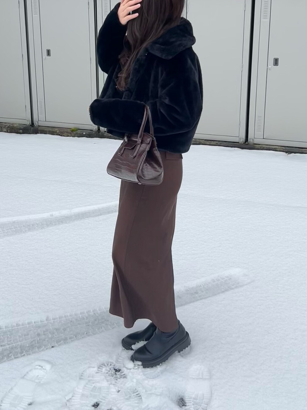 ブラック系のブルゾン、ブラウン系のスカート、ブラウン系のハンドバッグを着用したレディースの冬コーディネートの2枚目の写真