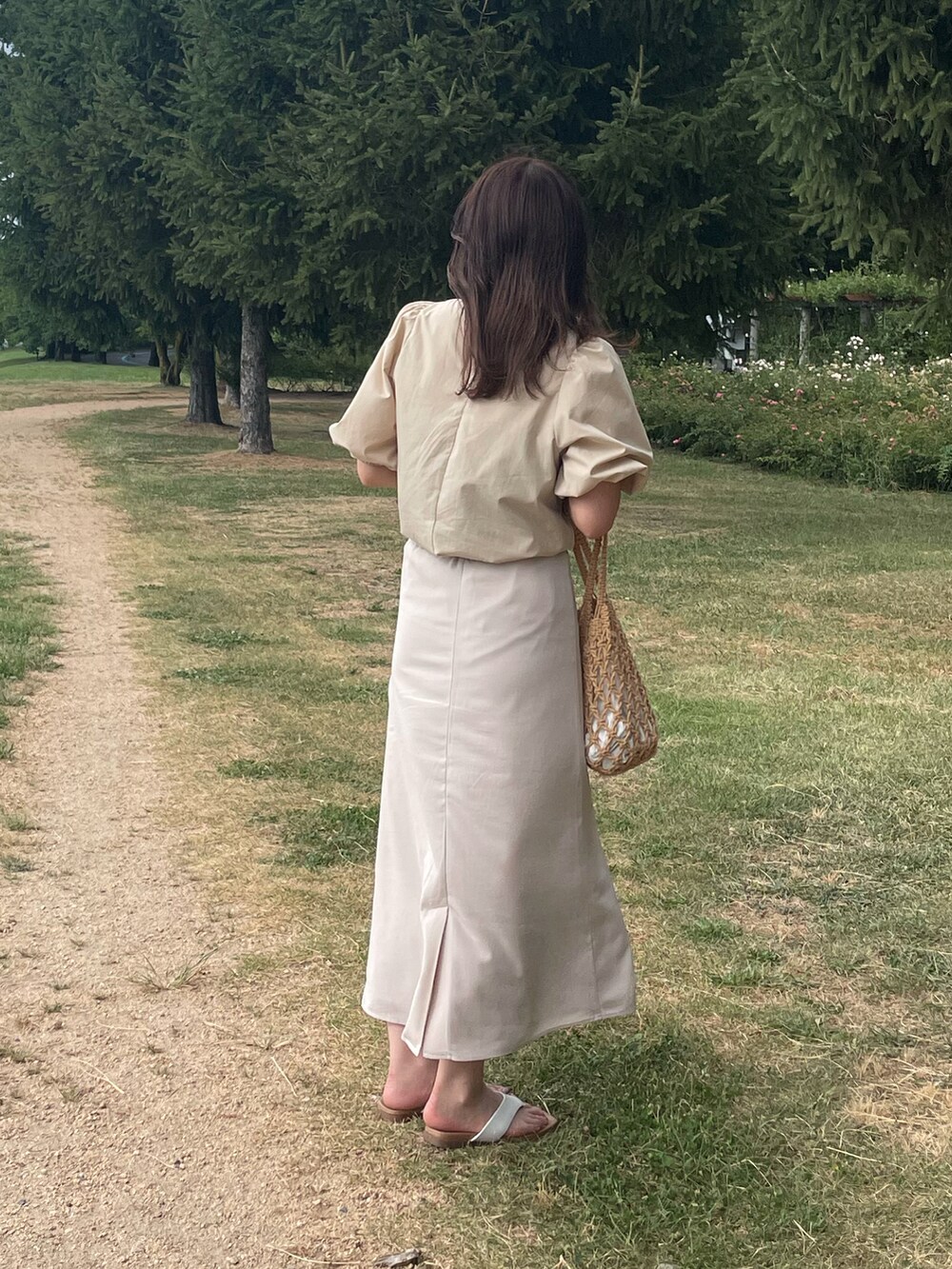ホワイト系のスカート、ベージュ系のハンドバッグを着用したレディースの夏コーディネートの3枚目の写真