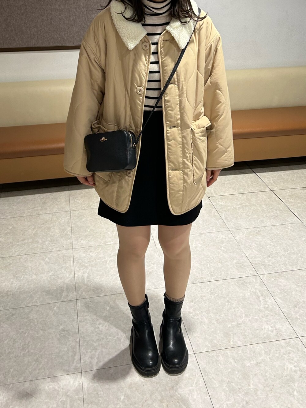 ベージュ系のミリタリージャケット、ブラック系のショルダーバッグ、ホワイト系のニット/セーターを着用したレディースの冬コーディネートの2枚目の写真