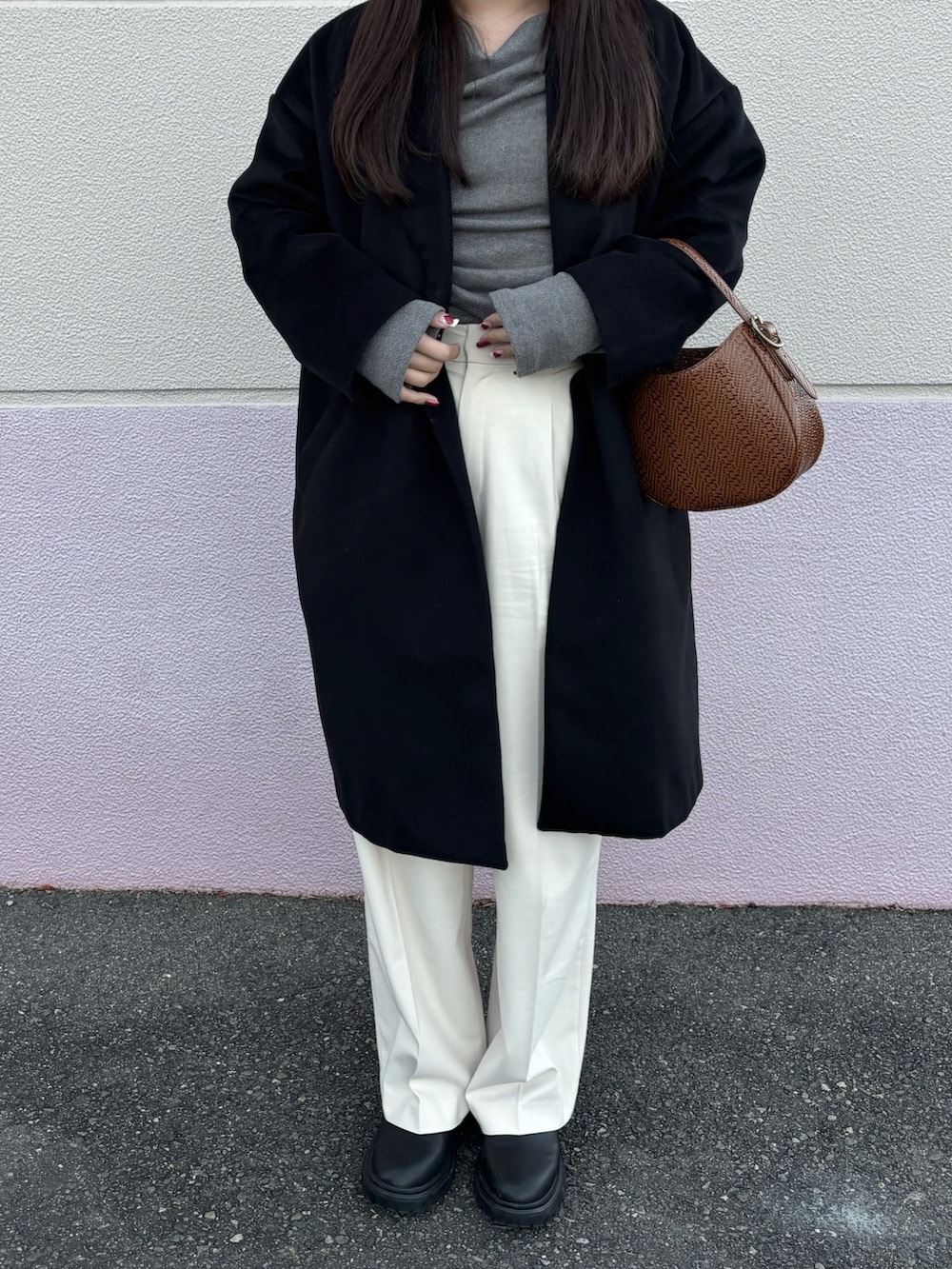 ブラック系のチェスターコート、ホワイト系のスラックス、グレー系のトップスを着用したレディースの冬コーディネートの2枚目の写真