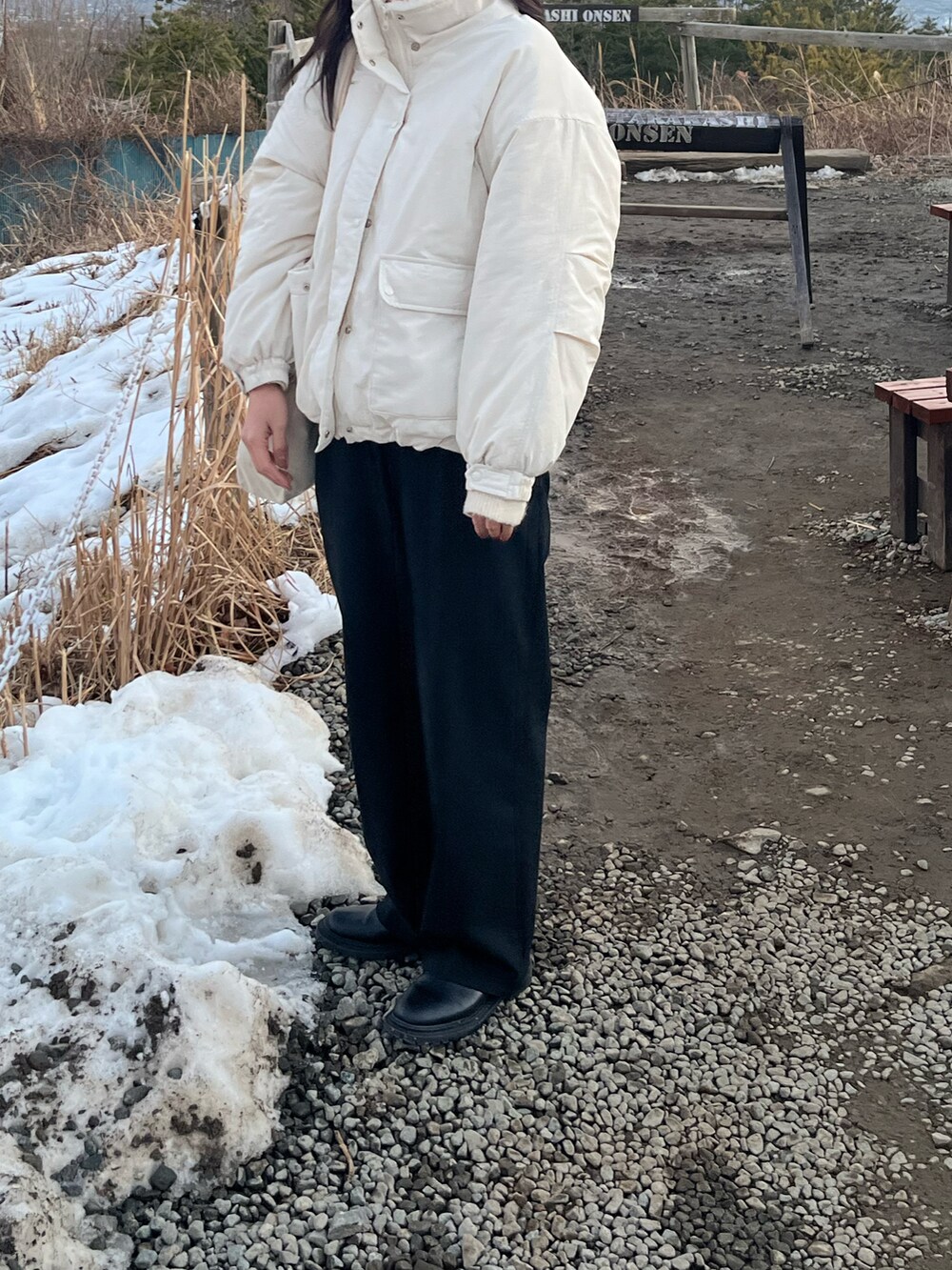 ホワイト系のブルゾン、ブラック系のスラックスを着用したレディースの春コーディネートの2枚目の写真