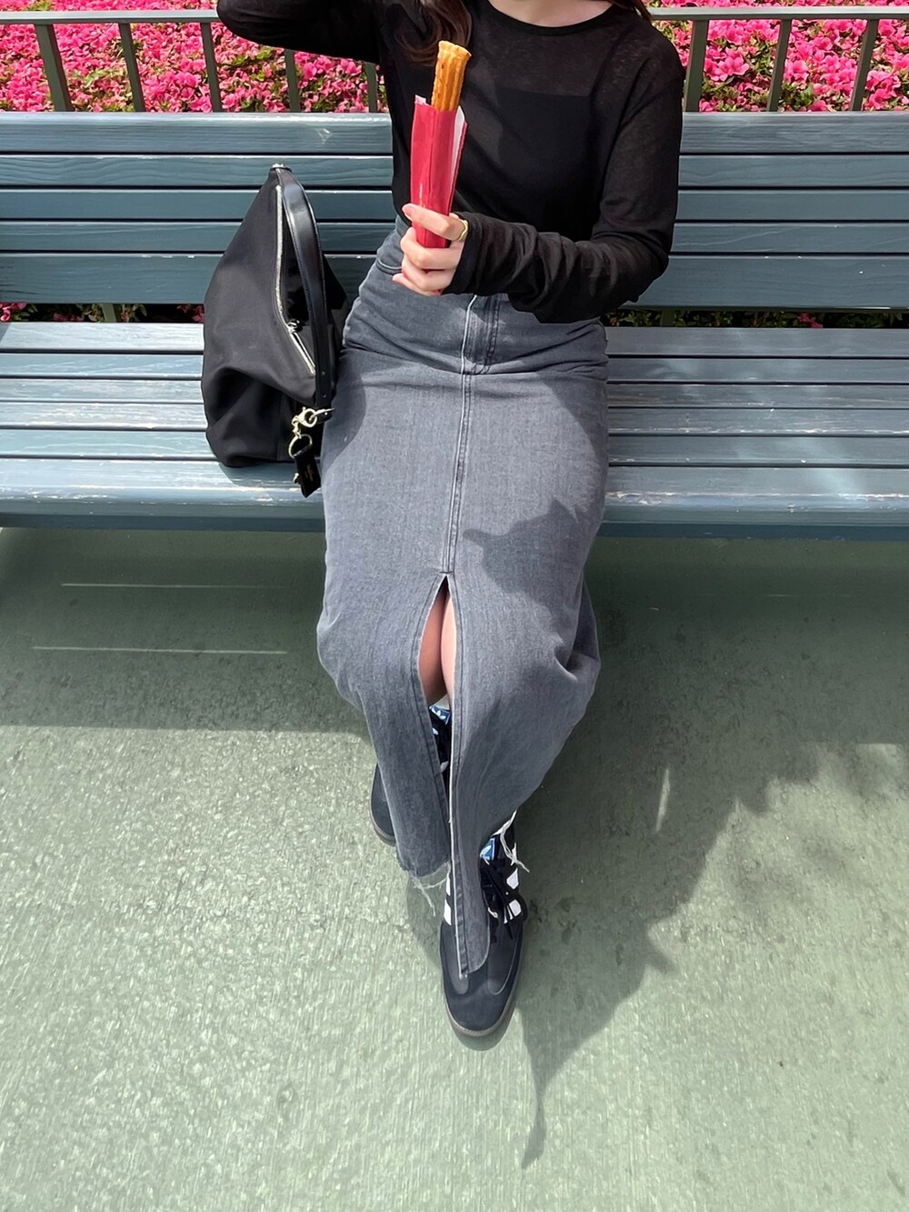 ブラック系のトップス、グレー系のデニムスカート、ブラック系のスニーカーを着用したレディースの春コーディネートの2枚目の写真