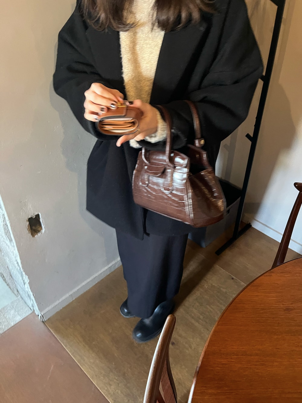 ブラウン系のハンドバッグ、ブラック系のスカート、ベージュ系のニット/セーターを着用したレディースの冬コーディネートの2枚目の写真