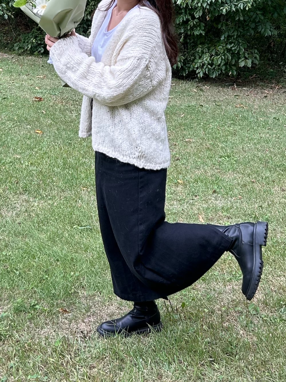 ブラウン系のバッグ、ブラック系のブーツを着用したレディースの秋コーディネートの2枚目の写真