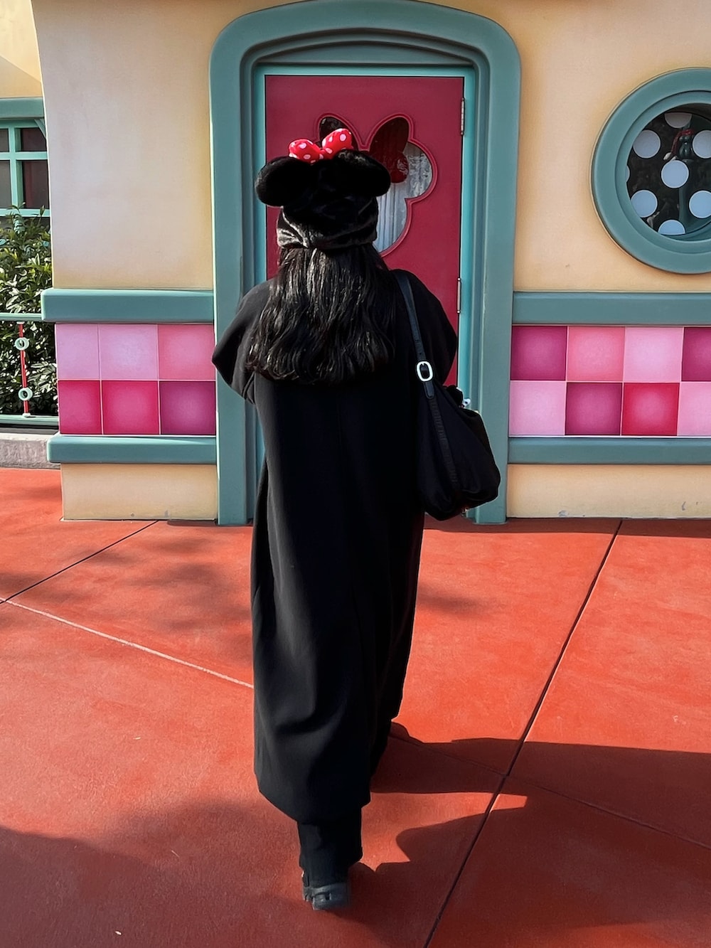 ブラック系のステンカラーコート、ホワイト系のニット/セーター、ブラック系のスニーカーを着用したレディースの冬コーディネートの2枚目の写真