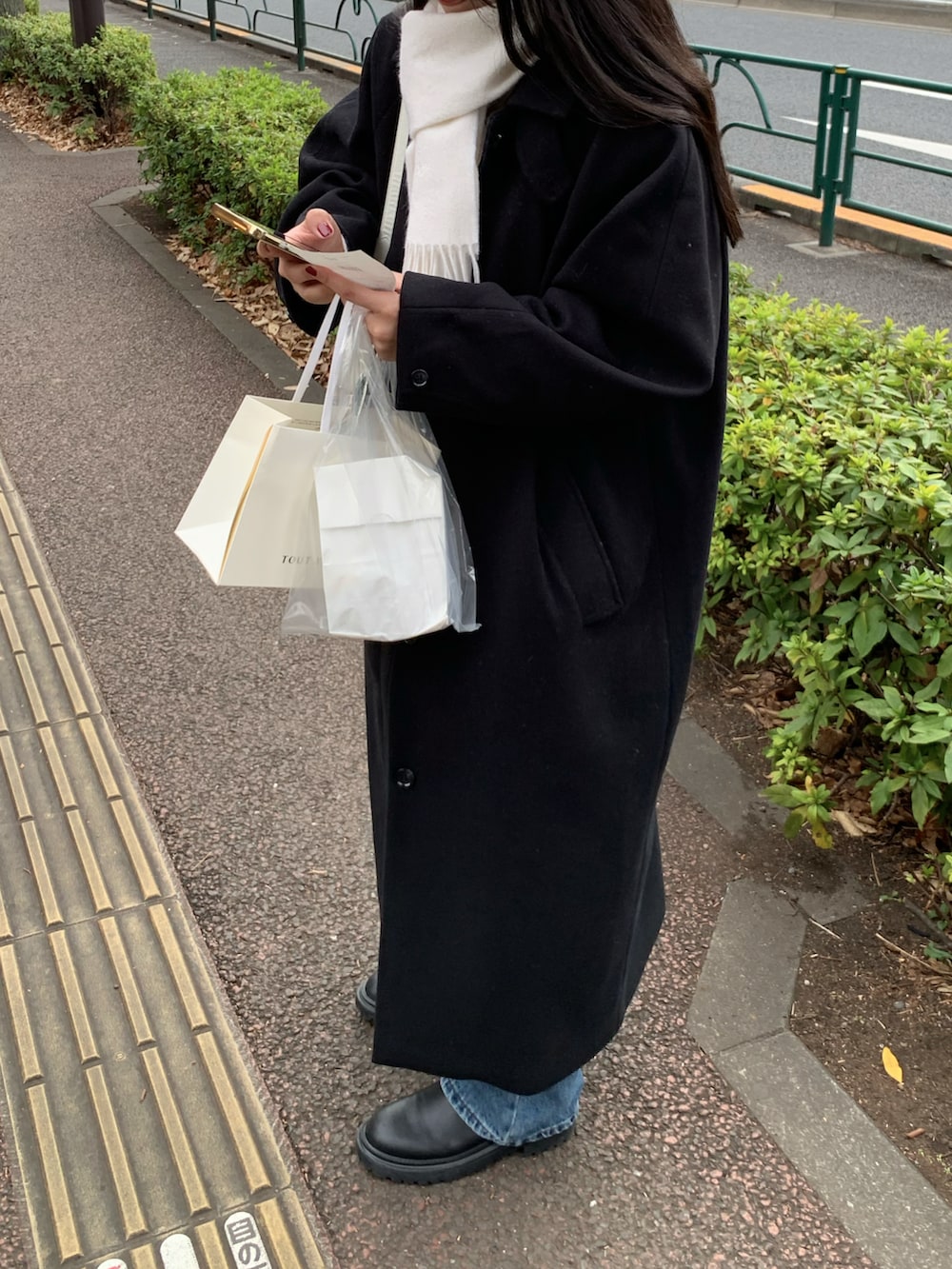 ブラック系のステンカラーコートを着用したレディースの冬コーディネートの2枚目の写真