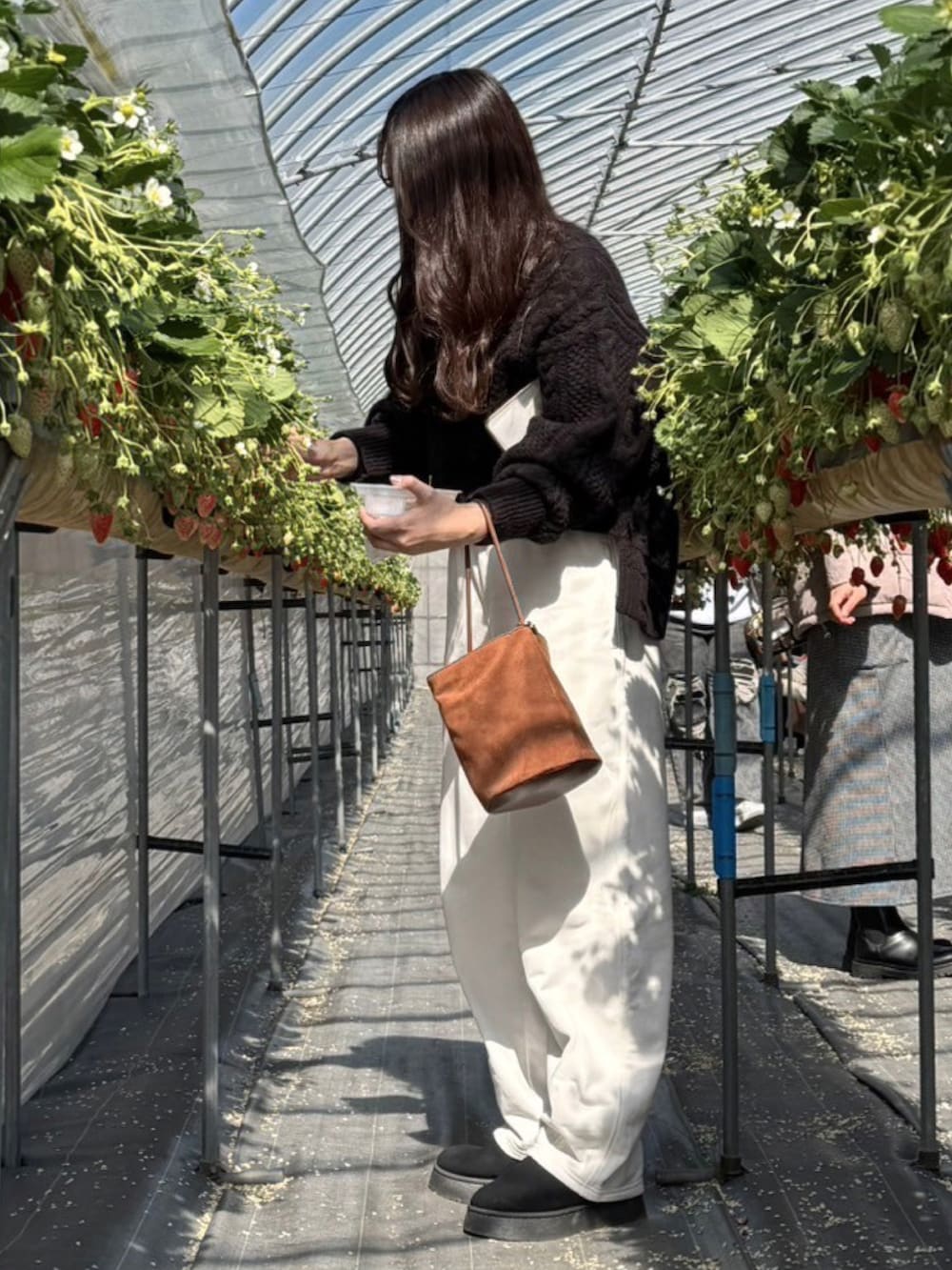 ブラック系のニット/セーター、ブラウン系のハンドバッグ、ホワイト系のスウェットパンツを着用したレディースの冬コーディネートの2枚目の写真