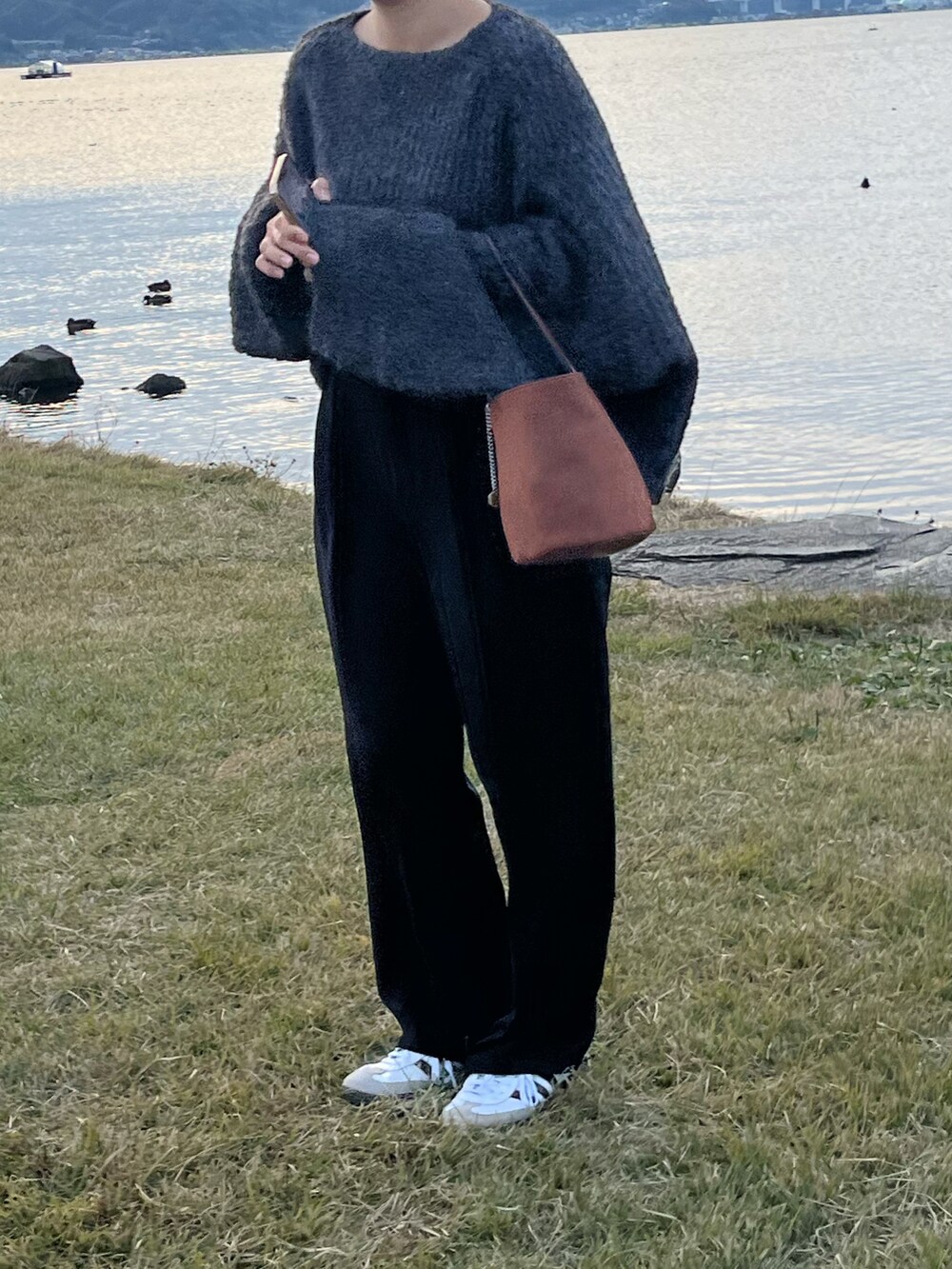 ブラウン系のハンドバッグ、ブラック系のスラックス、グレー系のニット/セーターを着用したレディースの秋コーディネートの2枚目の写真