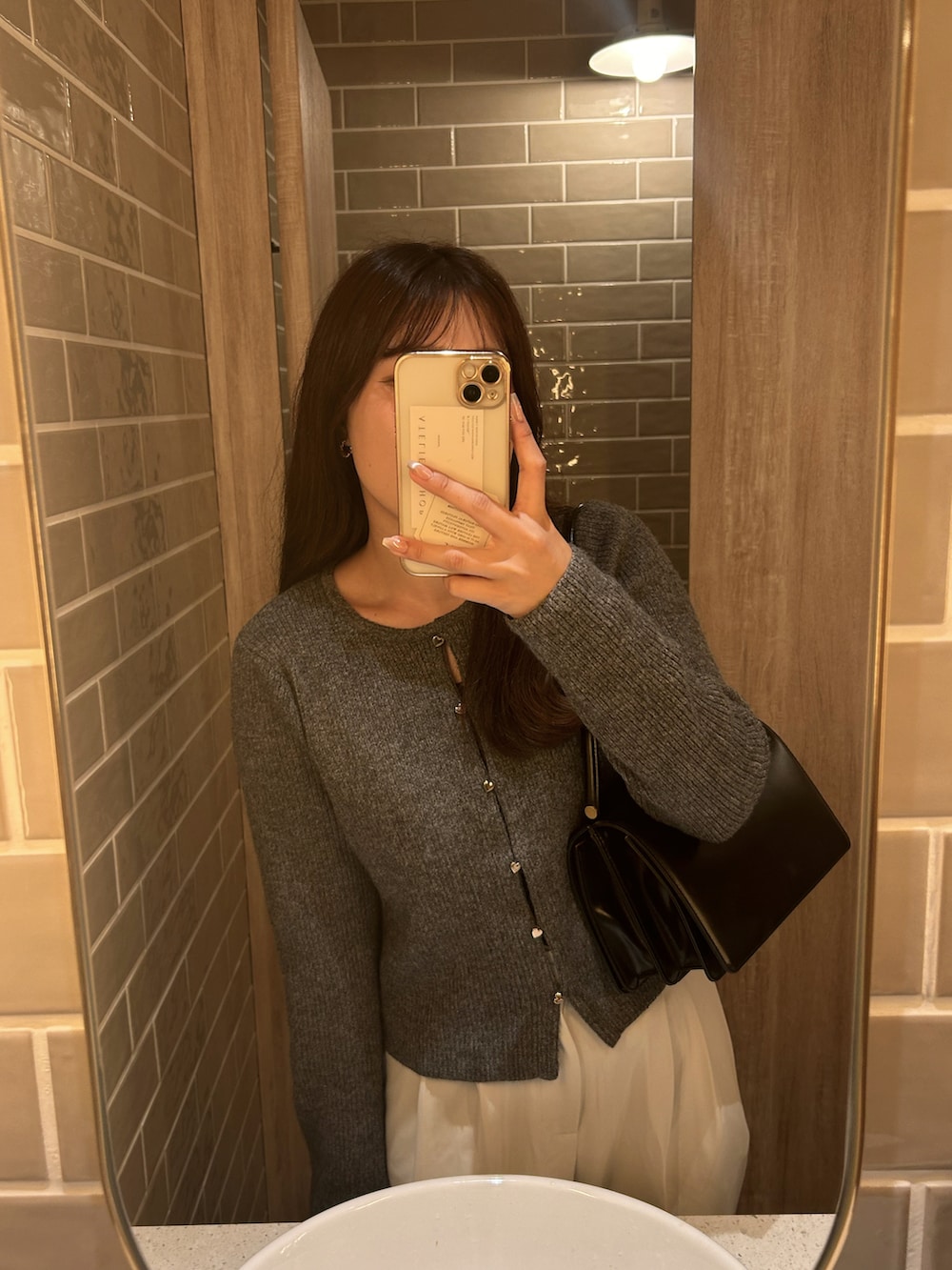 グレー系のカーディガン/ボレロ、ホワイト系のスラックスを着用したレディースの秋コーディネートの2枚目の写真