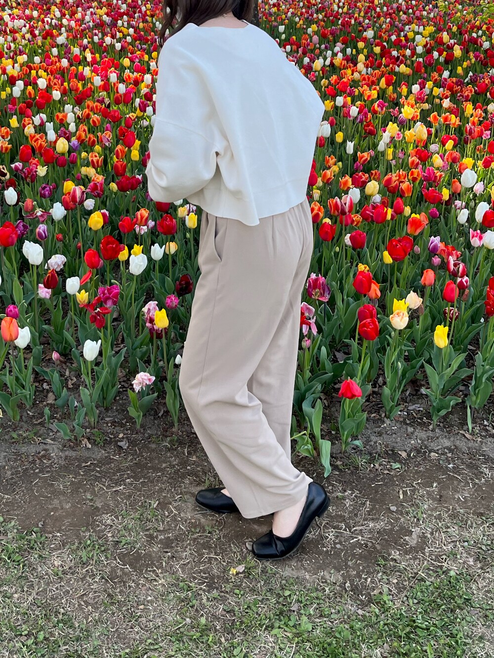 ホワイト系のカーディガン/ボレロ、ベージュ系のパンツ、ブラック系のハンドバッグを着用したレディースの春コーディネートの2枚目の写真