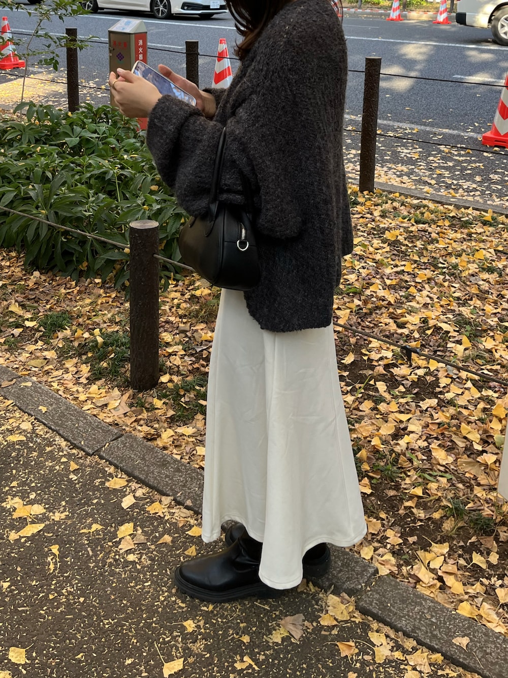グレー系のニット/セーター、ホワイト系のスカートを着用したレディースの秋コーディネートの2枚目の写真