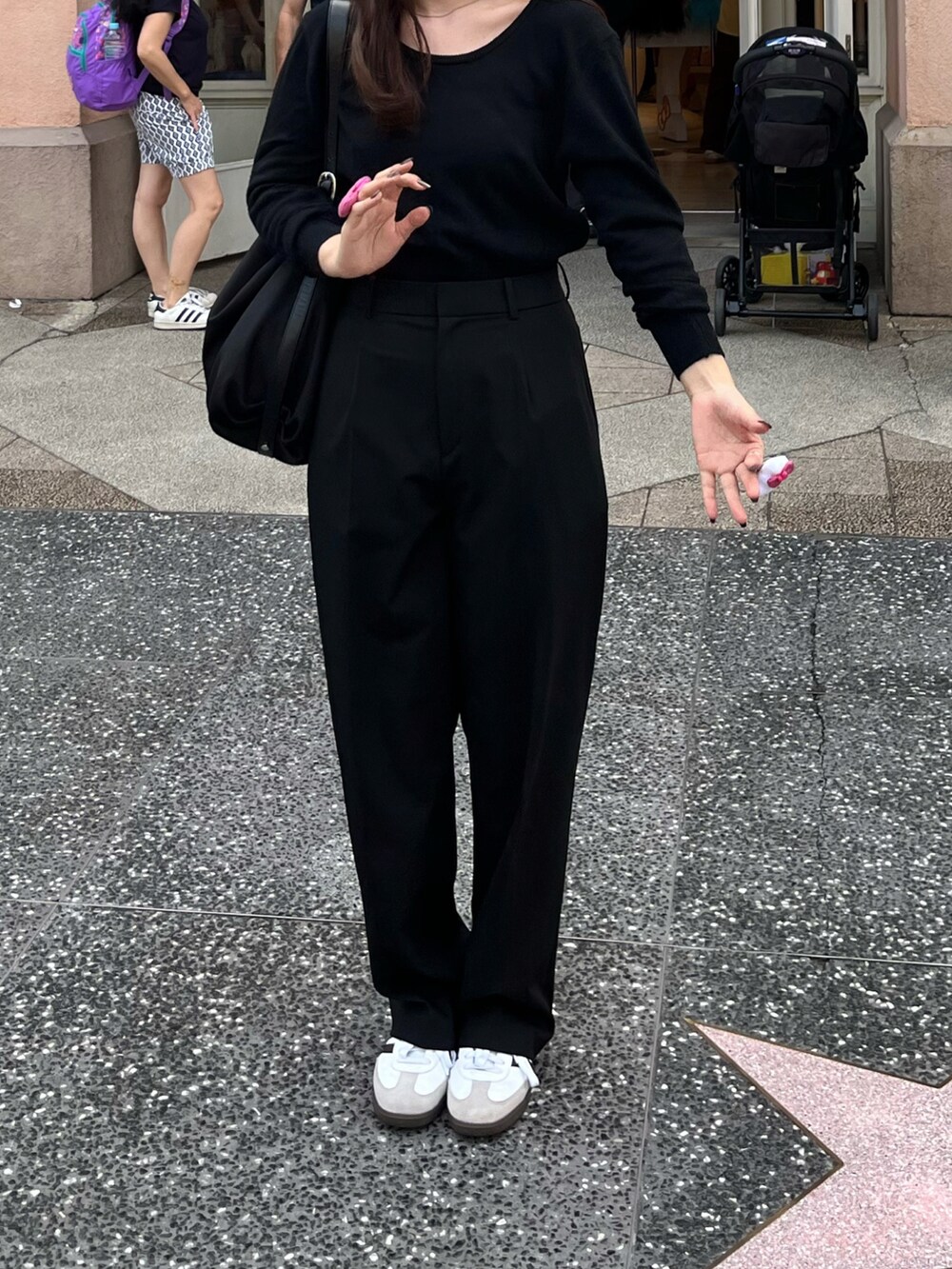 ブラック系のニット/セーター、ブラック系のスラックス、ホワイト系のスニーカーを着用したレディースの秋コーディネートの2枚目の写真