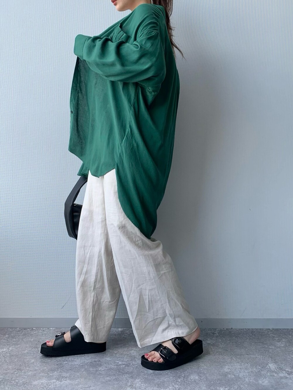 ブラック系のサンダル、ホワイト系のショルダーバッグ、グリーン系のトップスを着用したレディースの夏コーディネートの3枚目の写真