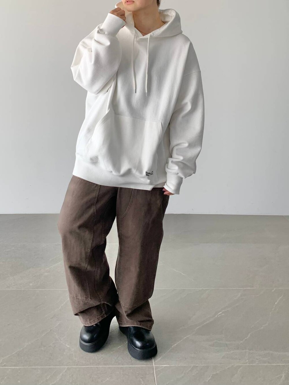 ブラウン系のデニムパンツ、ホワイト系のスウェット、ブラック系のサンダルを着用したレディースの夏コーディネートの2枚目の写真