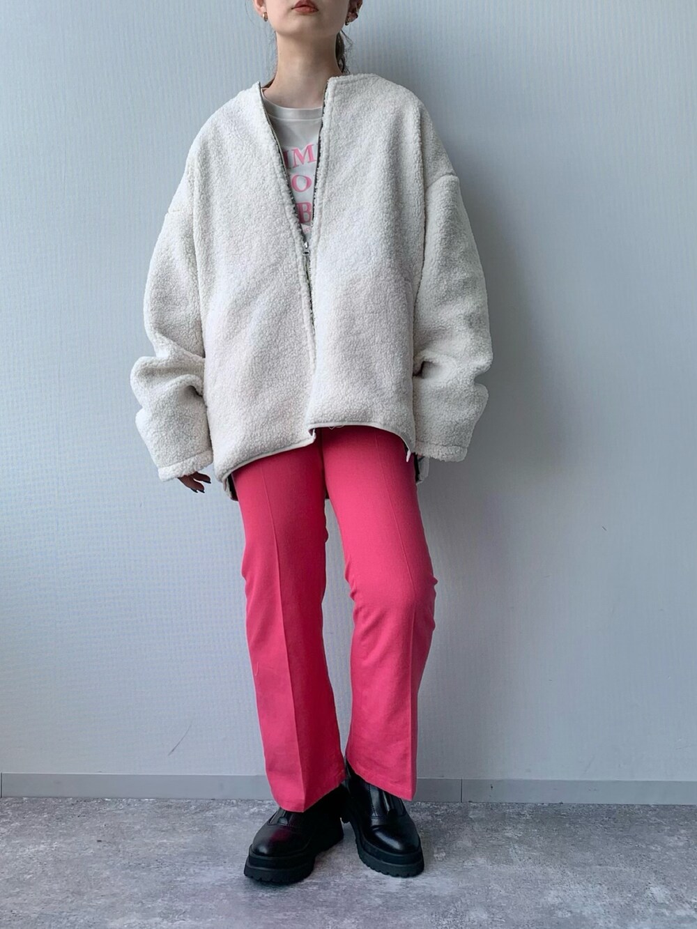 ホワイト系のブルゾン、ピンク系のスラックス、ブラック系のブーツを着用したレディースの夏コーディネートの5枚目の写真