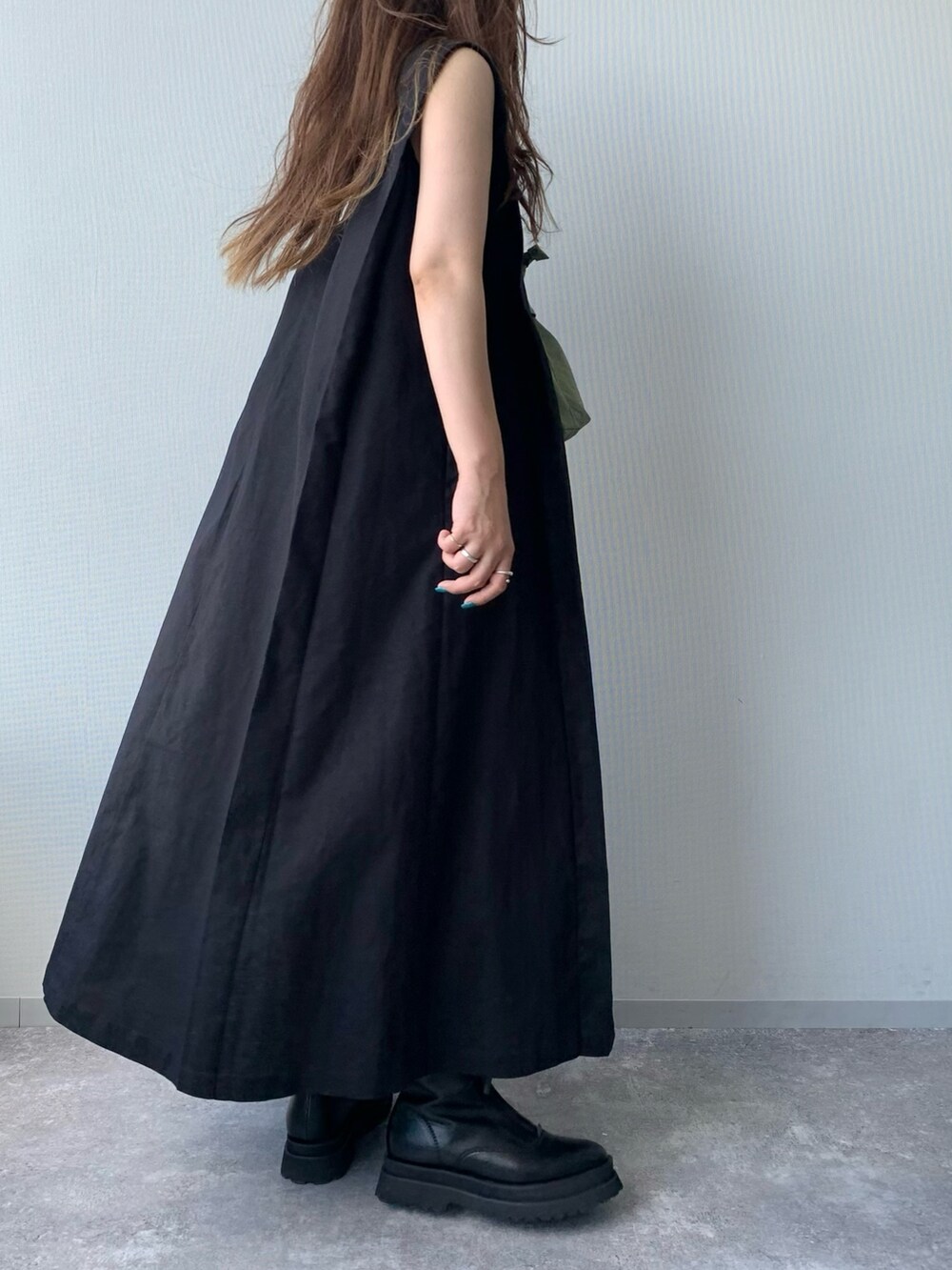 ブラック系のブーツ、ブラック系のワンピース、グリーン系のショルダーバッグを着用したレディースの夏コーディネートの3枚目の写真