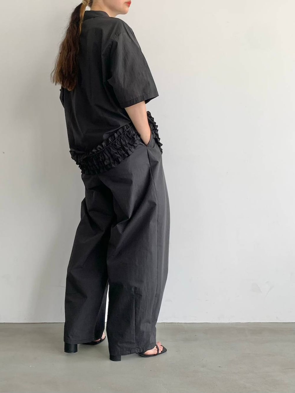 ブラック系のサンダル、ブラック系のスラックス、ブラック系のシャツ/ブラウスを着用したレディースの夏コーディネートの2枚目の写真