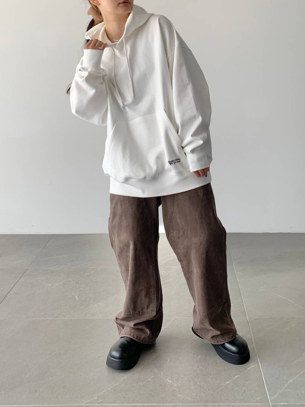 ブラウン系のデニムパンツ、ホワイト系のスウェット、ブラック系のサンダルを着用したレディースの夏コーディネートの4枚目の写真