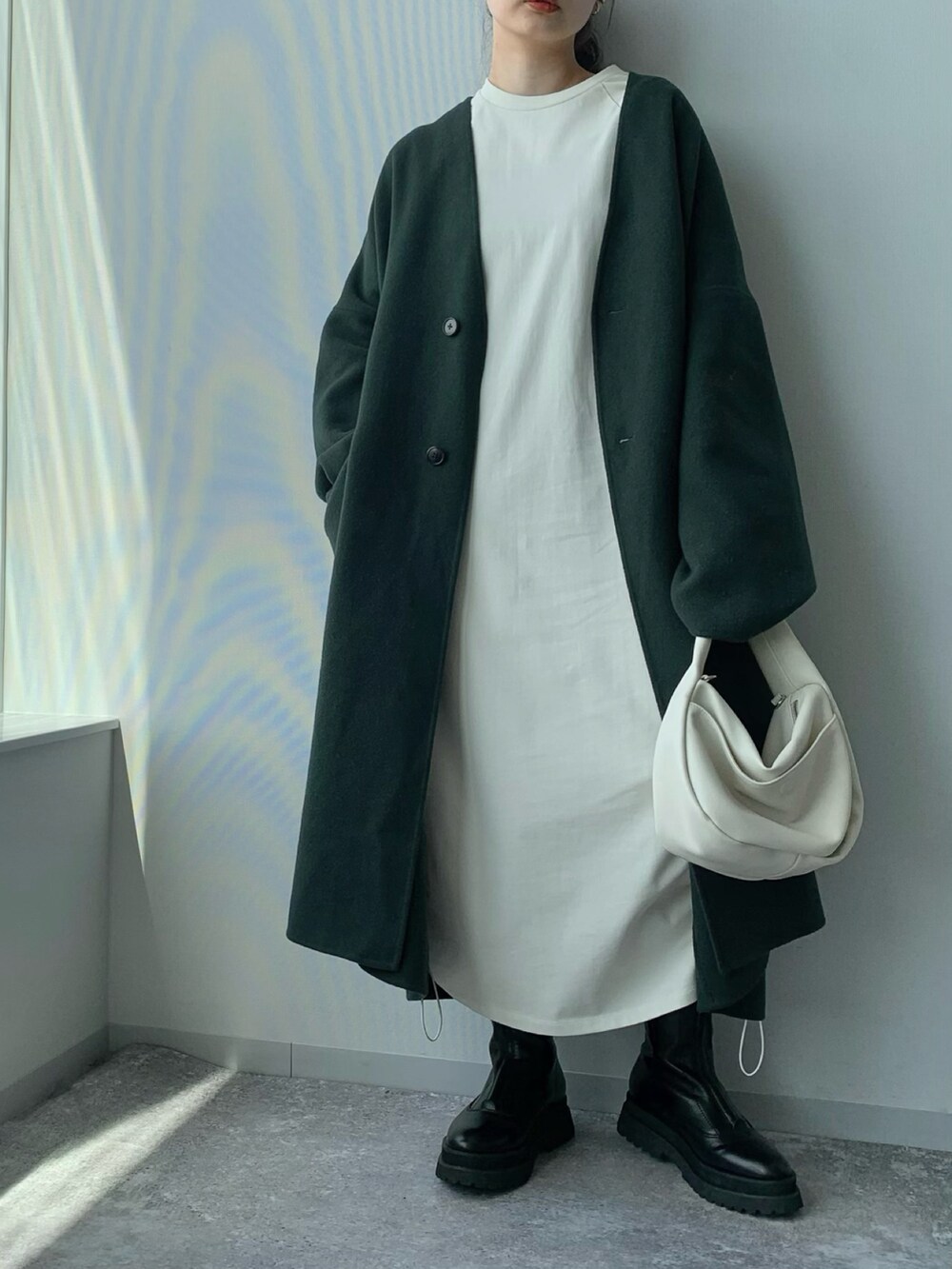ホワイト系のショルダーバッグ、ブラック系のブーツ、グリーン系のノーカラーコートを着用したレディースの夏コーディネートの4枚目の写真