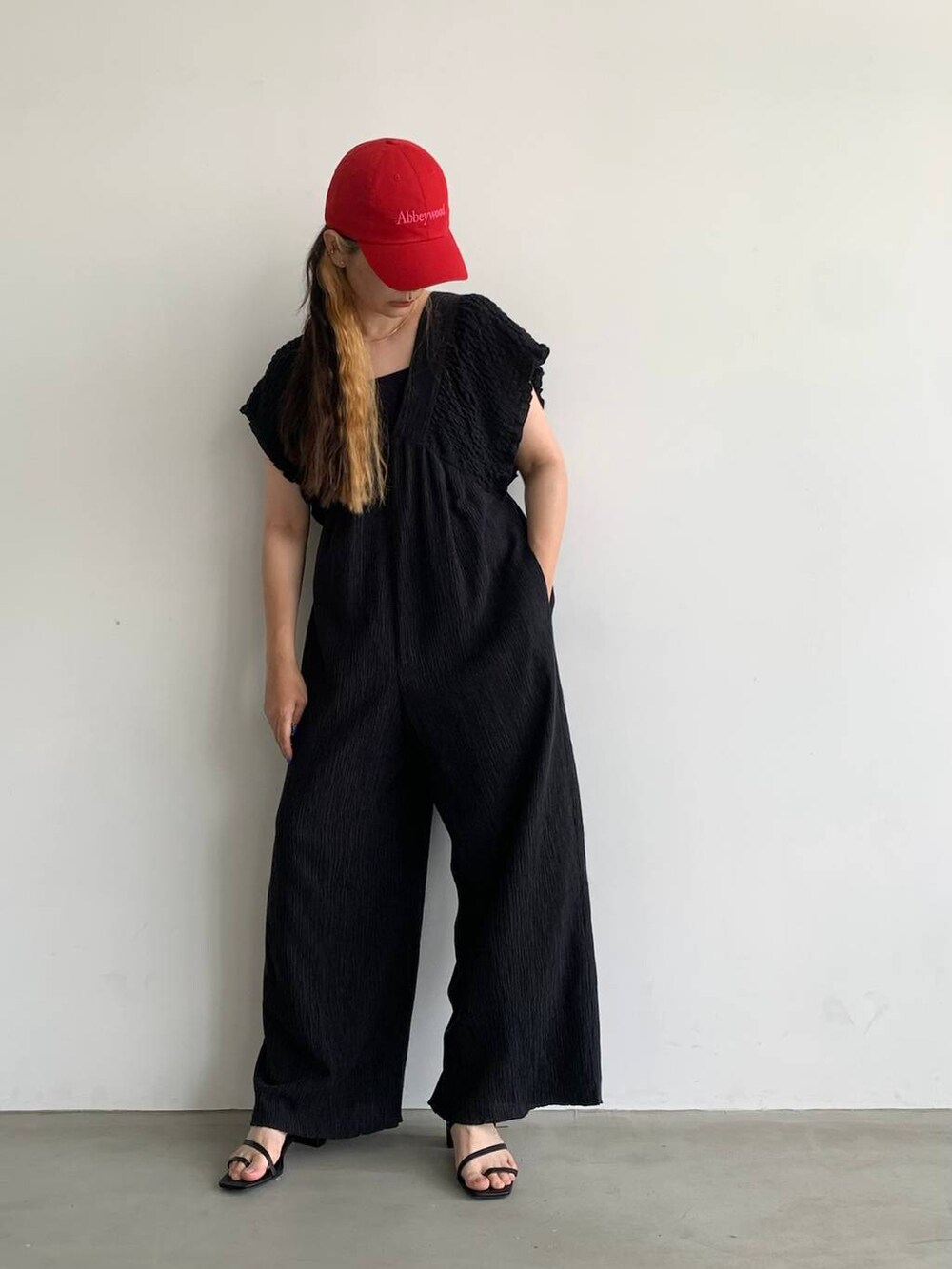 ブラック系のサロペット/オーバーオール、ブラック系のサンダル、レッド系のキャップを着用したレディースの夏コーディネートの2枚目の写真