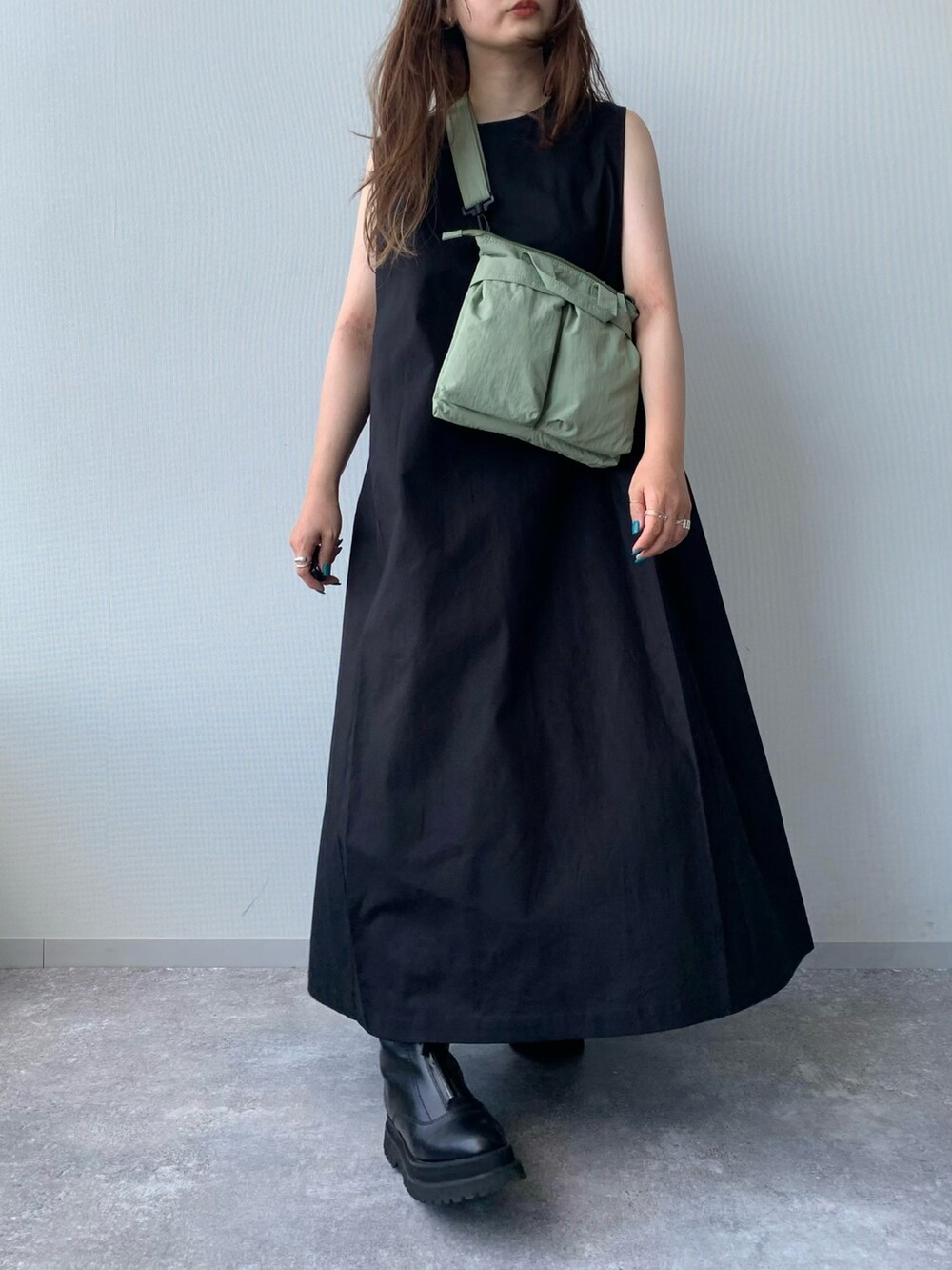 ブラック系のブーツ、ブラック系のワンピース、グリーン系のショルダーバッグを着用したレディースの夏コーディネートの5枚目の写真