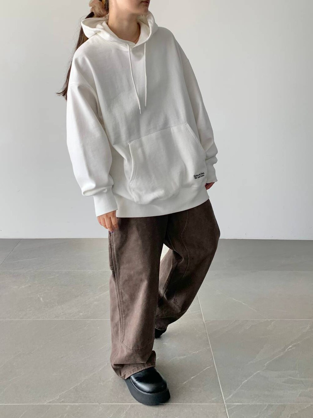 ブラウン系のデニムパンツ、ホワイト系のスウェット、ブラック系のサンダルを着用したレディースの夏コーディネートの7枚目の写真