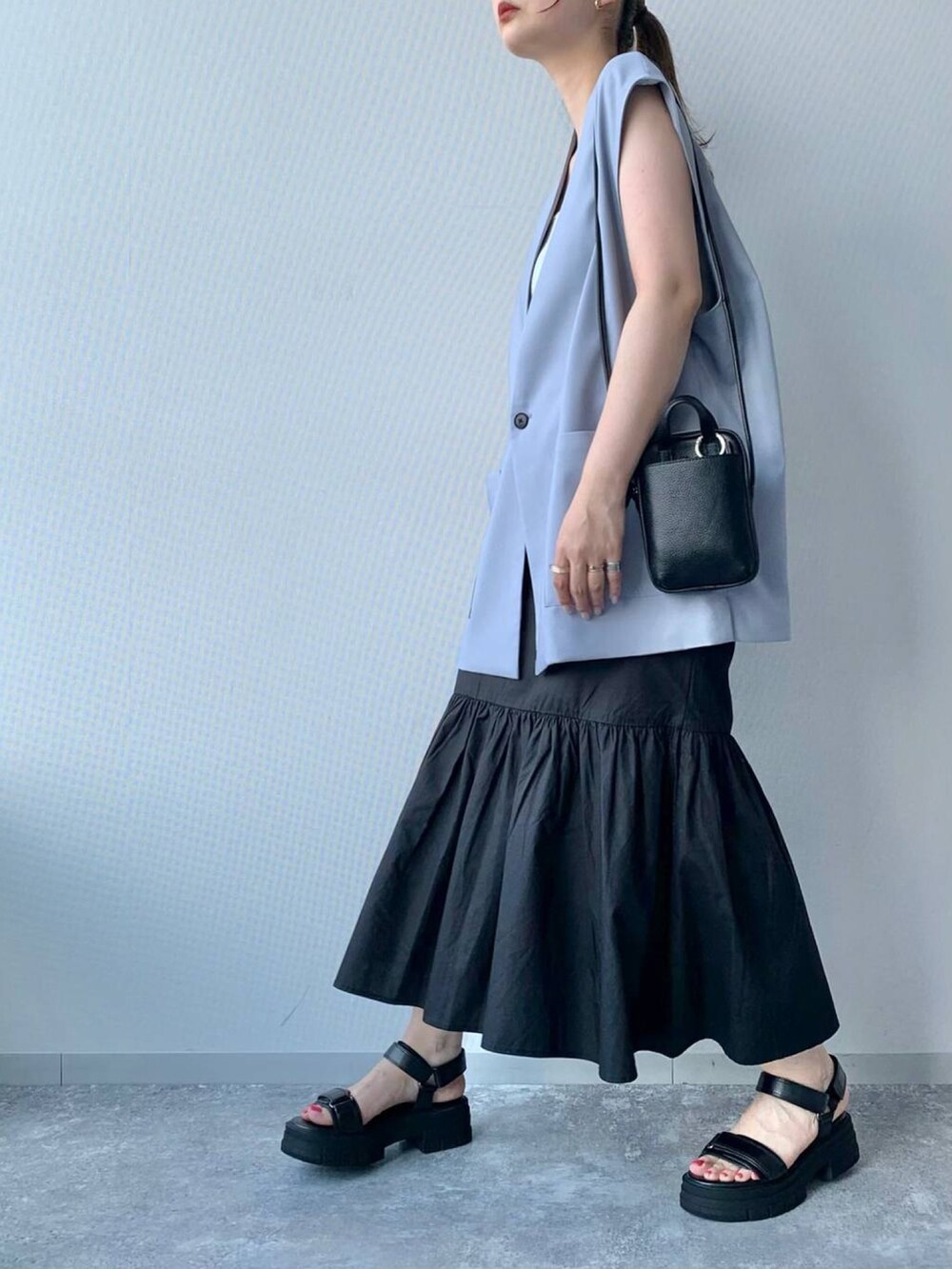 ブラック系のサンダル、ブラック系のスカート、ブラック系のショルダーバッグを着用したレディースの夏コーディネートの2枚目の写真