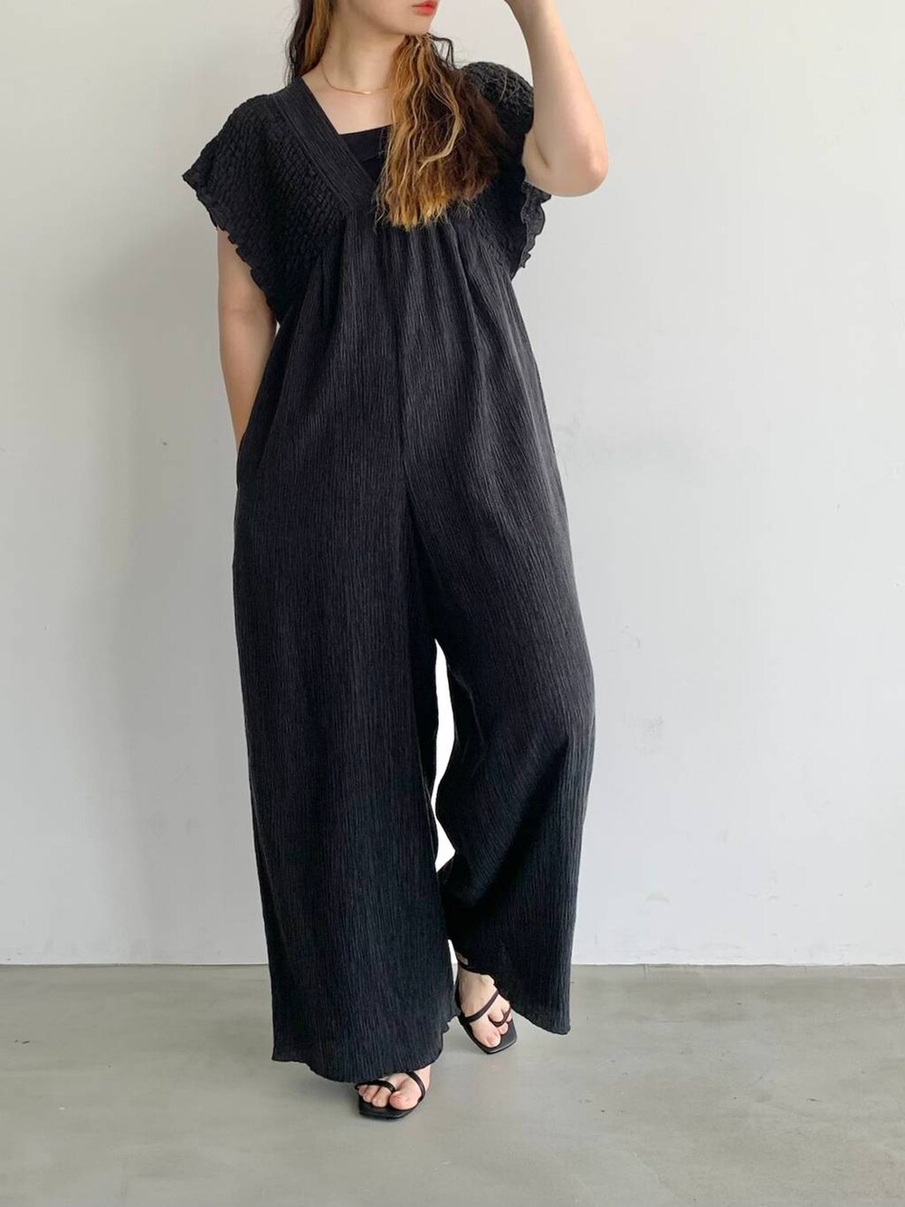 ブラック系のサロペット/オーバーオール、ブラック系のサンダル、レッド系のキャップを着用したレディースの夏コーディネートの4枚目の写真